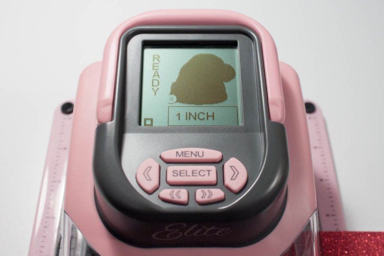 I created a 1-inch-wide die-cut of a Santa hat using my Slice and "Mistletoe" design card. First, I made a die-cut in red-glitter cardstock, then made another die-cut in white cardstock. I then cut out the fringe and pom-pom portions of the white die-cut and adhered them to the red die-cut.